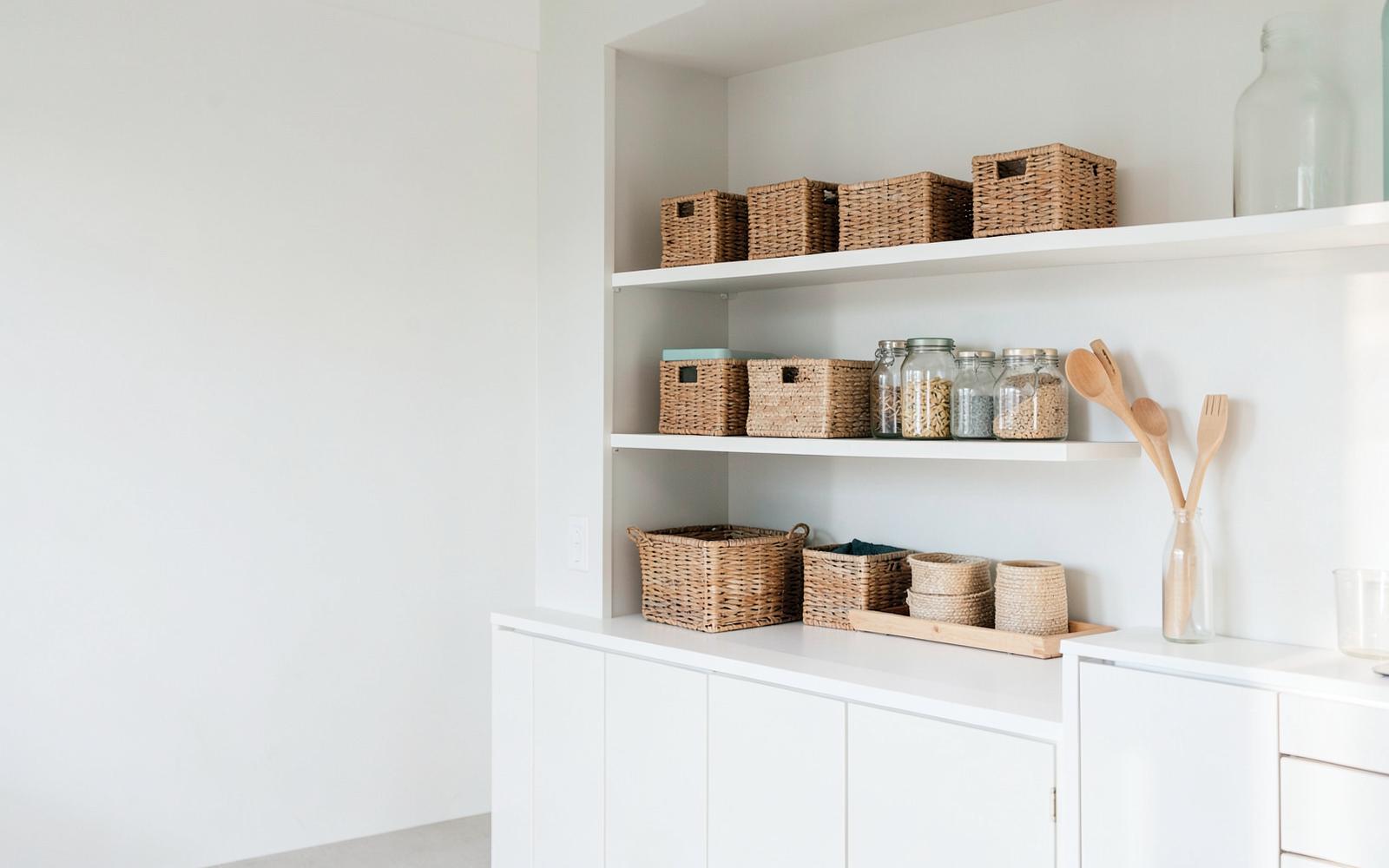 Bright kitchen shelving styled with woven storage baskets, glass jars and wooden utensils